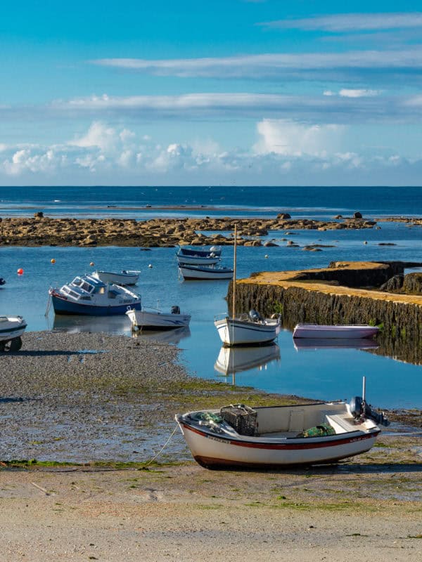 a yellow stone pier jutting out into the blue sea. point penmarc'h, brittany, france.